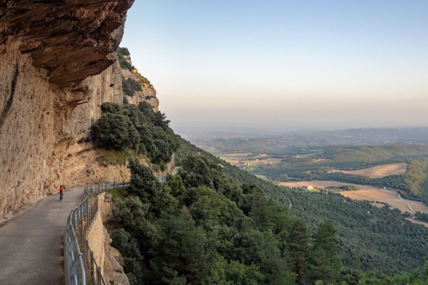 Cyclist riding along road within rock face - Malpas Capolat, Catalonia